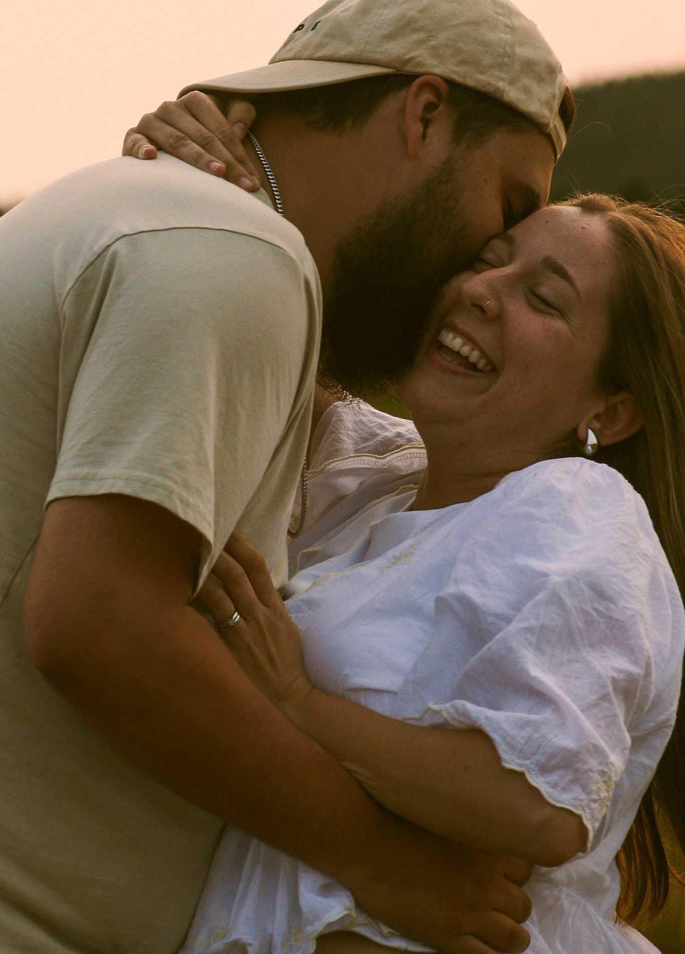 A couple laughing while embracing in warm sunset light