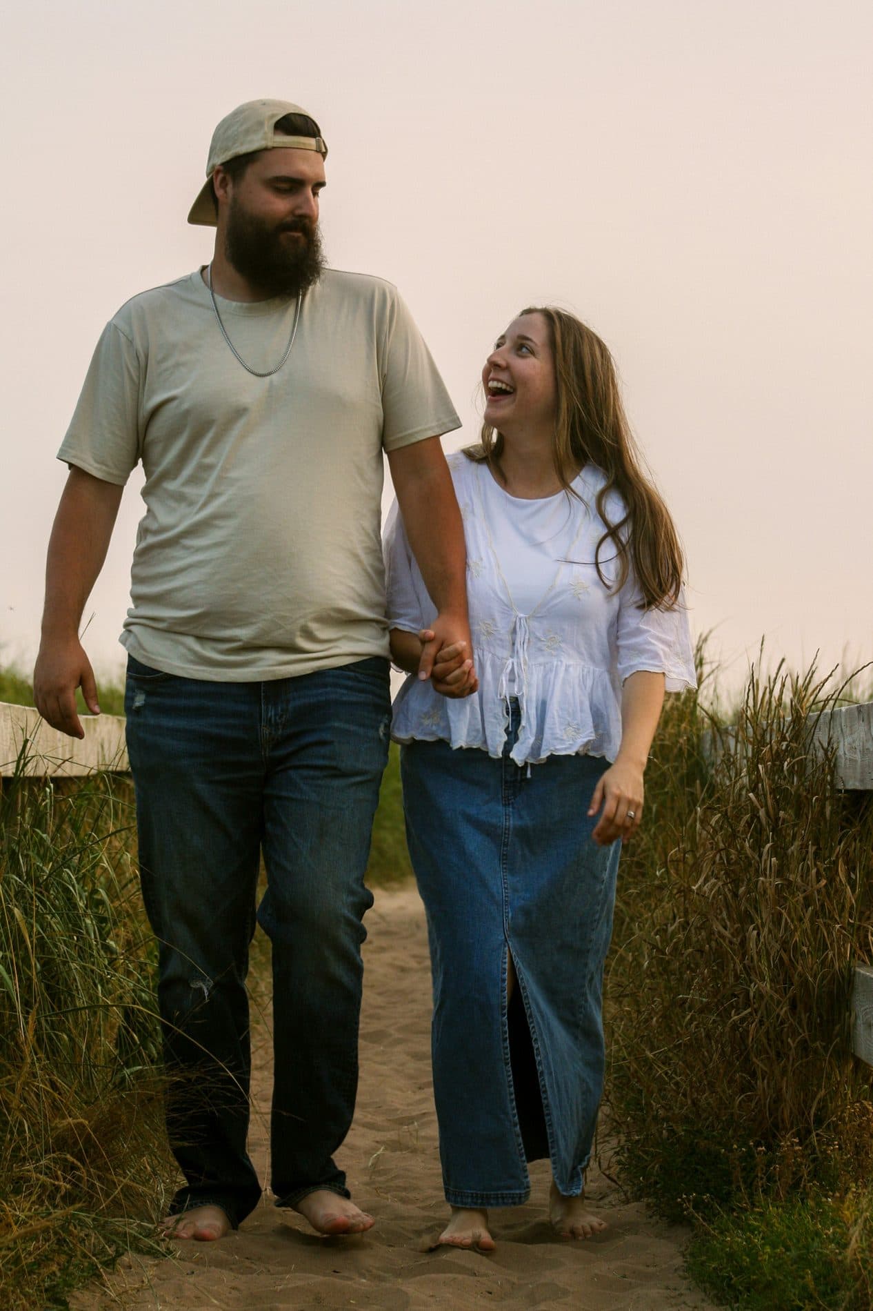 A couple walking hand in hand along a grassy coastal path