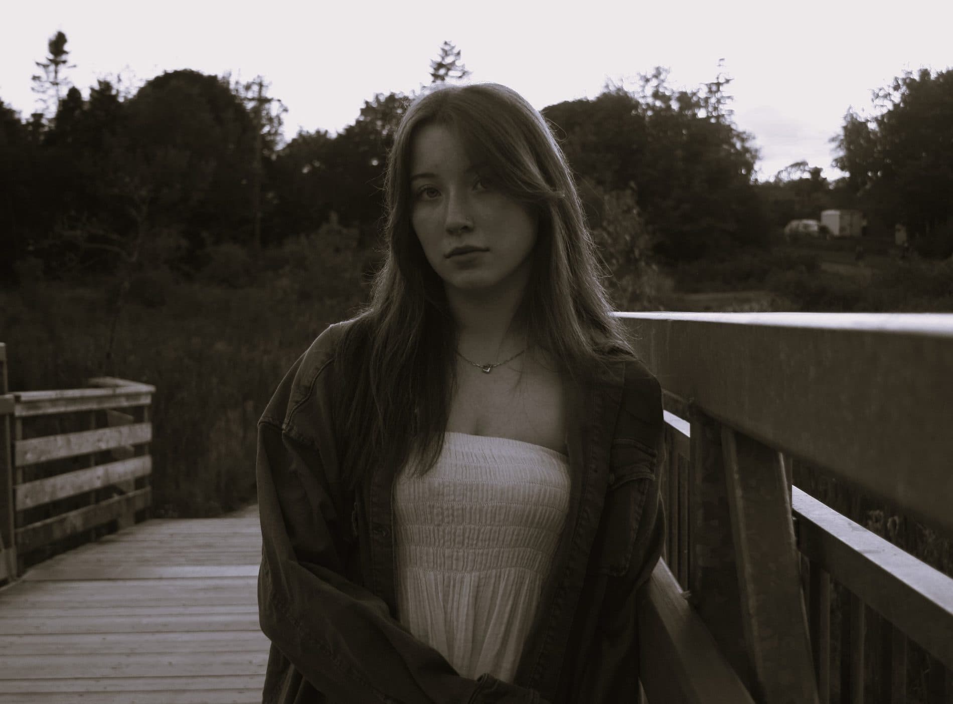 A portrait of a woman on a wooden bridge in muted evening tones