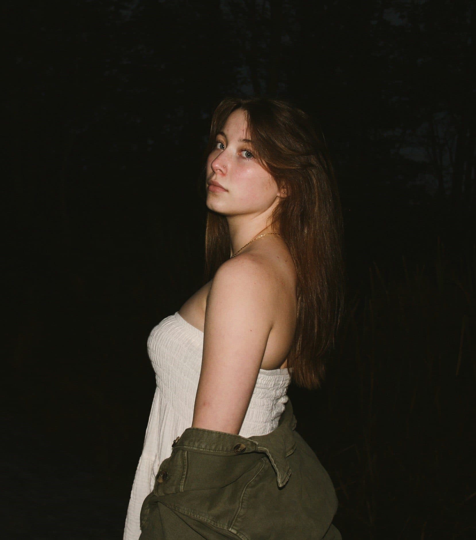 A portrait of a young woman against a deep shadowed background