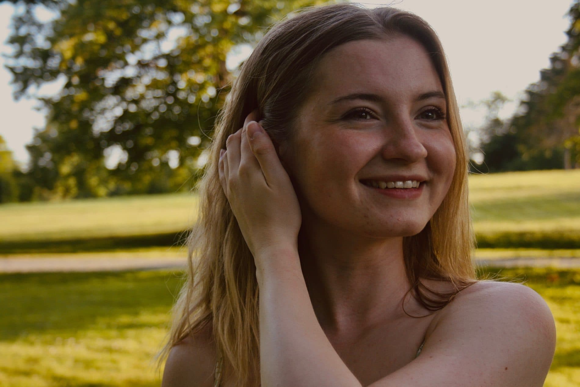 A portrait of a woman smiling in a sunlit field